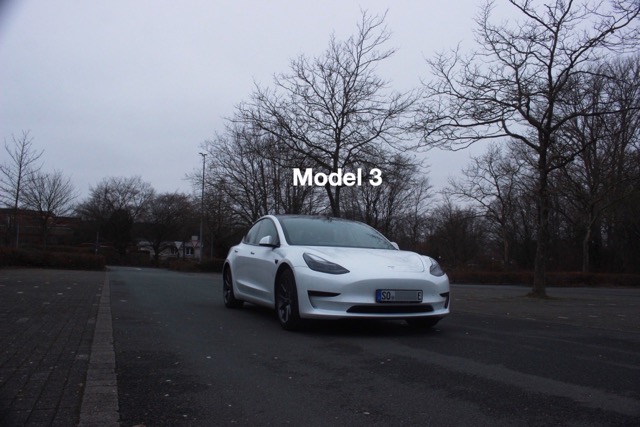 Weißes Tesla Model 3 auf dem Parkplatz der Börde Schule